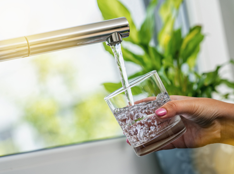 woman hand holds a glass to Filing it with water from tap
